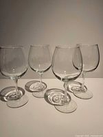 Four clear stemmed red wine glasses standing upright