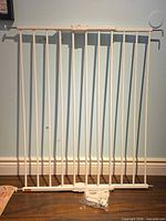 Front view of white metal safety gate with hardware bag at base