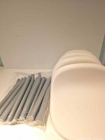 Unassembled parts: four white seats stacked and legs bagged