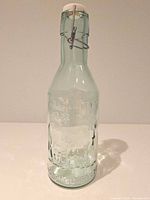 Full view of embossed glass milk bottle with stopper attached