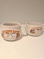 Two ceramic chicken soup recipe mugs side by side