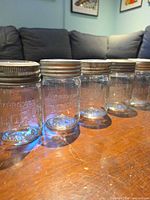 Five clear glass Corona pint mason jars with zinc rings lined up on table