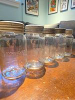 Five Corona jars lined up showing metal rings and glass bodies
