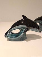 Side view of one dolphin figurine on teal wave base