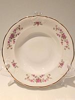 Front view of one bowl showing floral pattern, embossed rim and gold edge