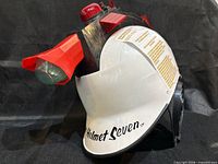 Front left view showing helmet, red light, projector, branding