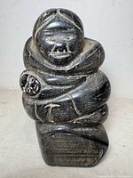 Front view of carved stone Inuit mother with baby figure