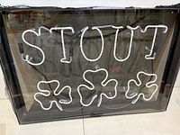 Front view showing STOUT letters and three shamrocks in white neon tubing