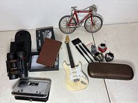 Group view of all items including bike, guitar, card holder, two binoculars, dart set