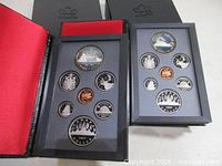 Both 1986 and 1987 coin sets opened showing seven coins each in display cases