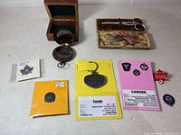 Overview of all items: compass in box, sewing kit open, enlistment pin, police pins, Olympic pin