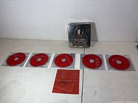 Full set laid out: five red CDs, booklet, and tin box