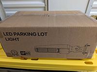 Sealed box labeled "LED PARKING LOT LIGHT" with IP65 icon and fixture graphic