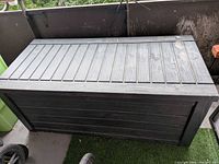 Closed gray plastic/resin deck box on balcony floor