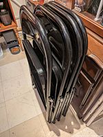 Four folded black metal chairs leaning against cabinet