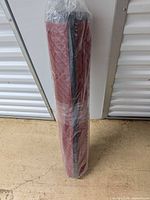 Rolled, plastic-wrapped red runner standing upright