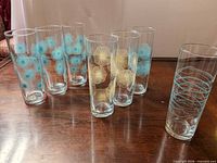 All seven clear glass highball glasses showing blue and gold floral sunburst and blue wavy line patterns