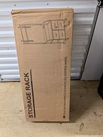 Sealed shipping box showing outline drawing of stand with drawers and mount