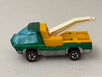 Left side profile showing green cab, yellow bed, white tow arm, redline wheel