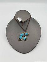 Front view of pendant showing turquoise stones and silver setting on display bust