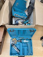 Overview of cardboard box with multiple Makita tools, polisher and drill case