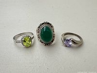 Front view of three silver-tone rings showing stone colours and settings