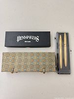 Three boxed sets: Penmakers box, clear box with two gold-tone instruments, patterned brocade box