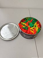 Tin container with lid removed showing dinosaurs