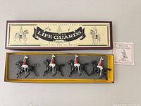 Full boxed set with lid removed showing four mounted figures in foam tray and pamphlet beside