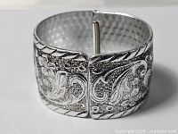 Front view of silver plate cuff showing floral Art Nouveau motif and hinged gap