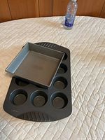 Muffin pan and square pan on bed surface