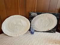 White ceramic turkey platter next to original box and water bottle for scale