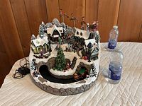 Full view of animated Christmas village with power adapter beside for scale