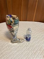 clear boot container filled with matchbooks next to water bottle for scale