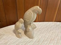 Front view of both marble parrot sculptures on quilted surface