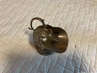 Angled view of silver plated gravy boat with ladle resting inside