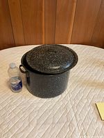 Speckled enamelware stock pot with lid beside water bottle for scale