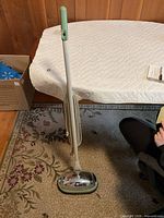 Full view of the vintage General Electric floor polisher standing upright with cord and handle visible