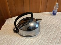 Side view of chrome General Electric electric kettle on quilted surface