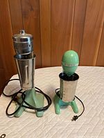 Two green Hamilton Beach milkshake mixers with their stainless steel cups