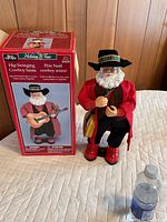Hip Swinging Cowboy Santa figure standing next to its original box