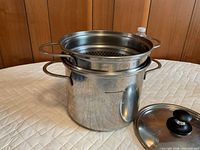 Lagostina stainless steel stock pot with strainer insert and lid displayed together