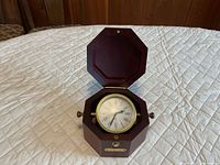 Open octagonal wood box showing Jerger clock with Roman numeral dial