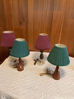 Four table lamps arranged on table showing shades, bases and cords