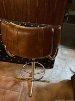Rear view of one brown leather swivel bar chair on chrome pedestal base