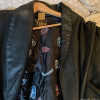 Front view of black leather jacket on hanger, showing Pervin label and patterned lining