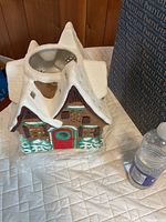 Ceramic gingerbread house candle holder next to water bottle for scale