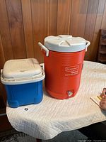 Front view of orange Gatorade beverage cooler and blue Igloo cooler