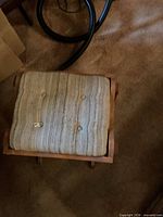 Overall view of wooden rocking foot stool showing cushion and rocker base