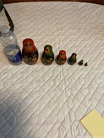 Seven nested dolls shown next to water bottle for scale
